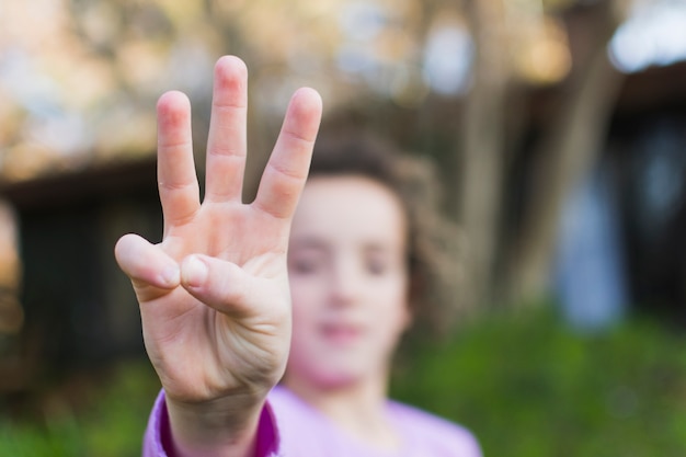 A girl showing three finger salute hand gesture