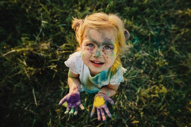 Girl shows her little palms covered with colorful paints