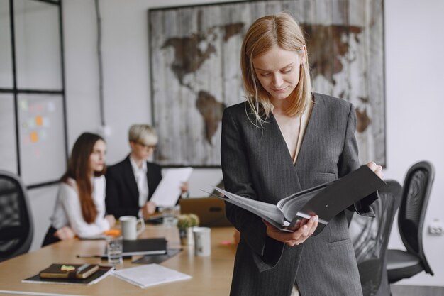 Girl signs the documents.  Lady sitting on the table. Manager working in the office.