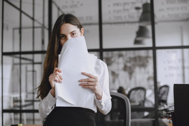 女の子は文書に署名します。オフィスで働くマネージャー。カメラを見ている女性。