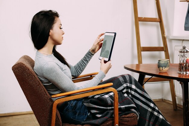 Free photo girl sits on cosy chair under black plaid