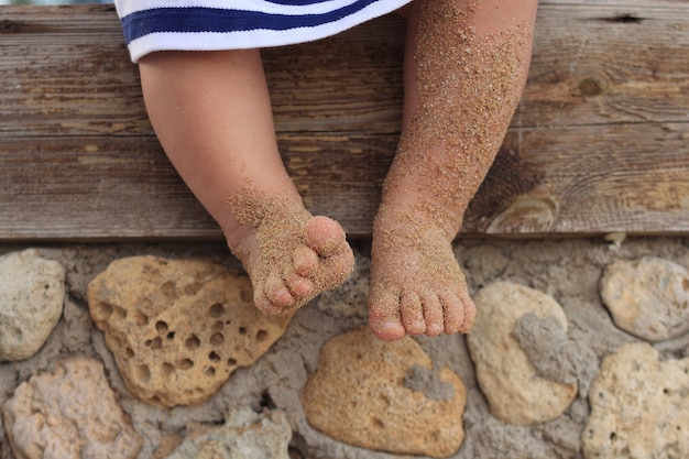 girl sits weighing her children's legs in the sand