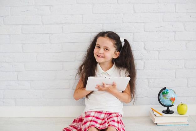 Girl sitting against white wall smiling