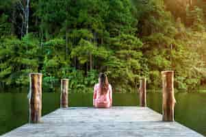 Free photo girl sitting alone on a the wooden bridge on the lake. pang ung, thailand.