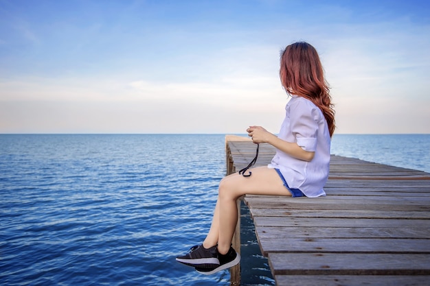 Girl sitting alone on a the wooden bridge on the sea. Vintage tone style.