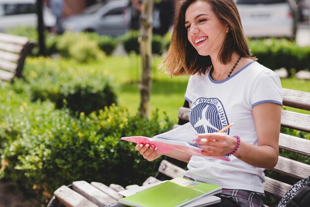 Girl sitting on bench holding notebook smiling