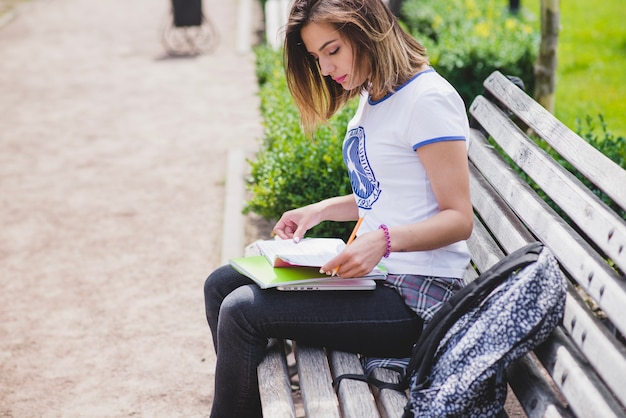 Girl sitting on bench holding notebooks studying