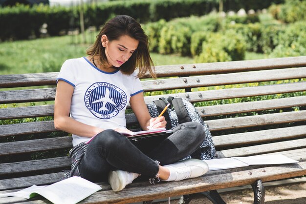 Girl sitting on bench in park studying