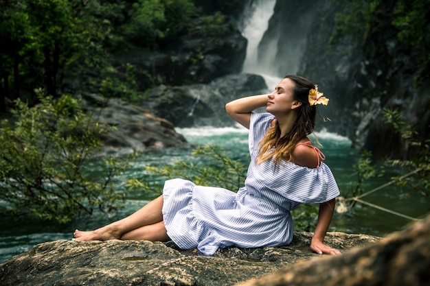 滝のそばに座っている女の子