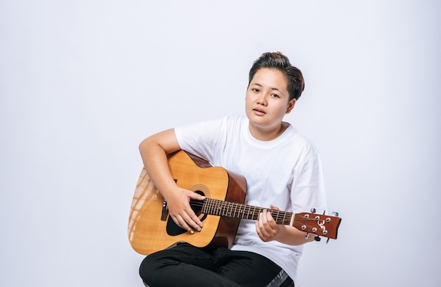 Girl sitting on a chair and playing guitar.