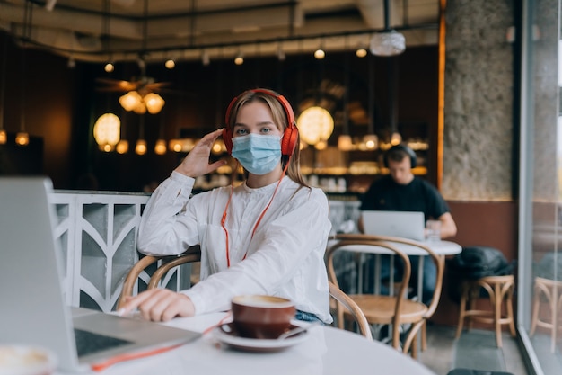 A girl sitting in a coffee shop with headphones coronavirus outbreak