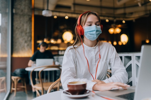 A girl sitting in a coffee shop with headphones coronavirus outbreak