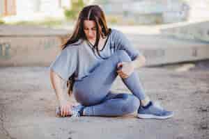 Free photo girl sitting on concrete floor stretching