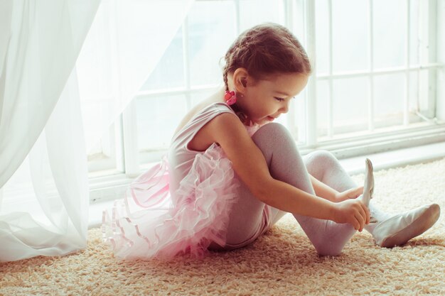 "Girl sitting on floor putting on shoes"