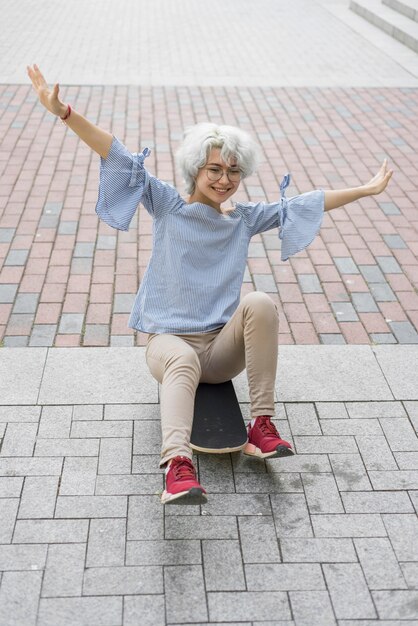 Girl sitting on her skateboard outside