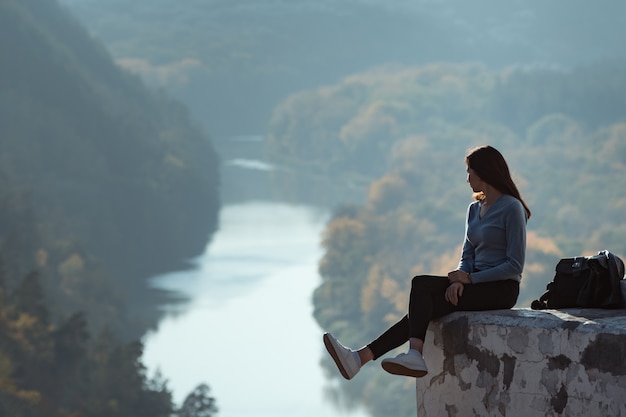 Premium Photo | Girl sitting on the hill and looks into the distance of the  forest and the river.