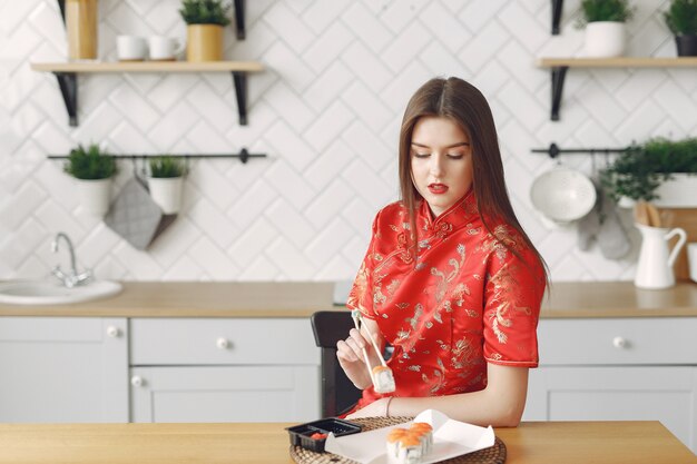 Girl sitting at home at the table with a sushi