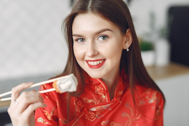 Girl sitting at home at the table with a sushi