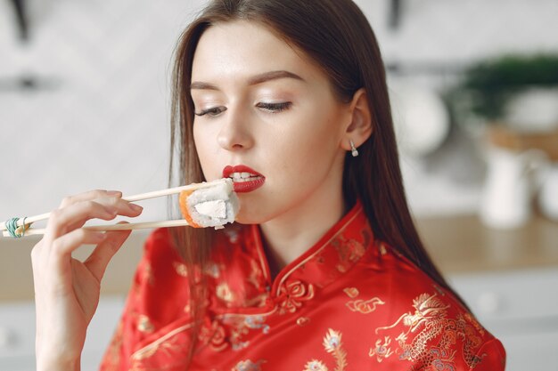 Girl sitting at home at the table with a sushi