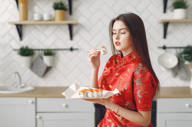 Girl sitting at home at the table with a sushi