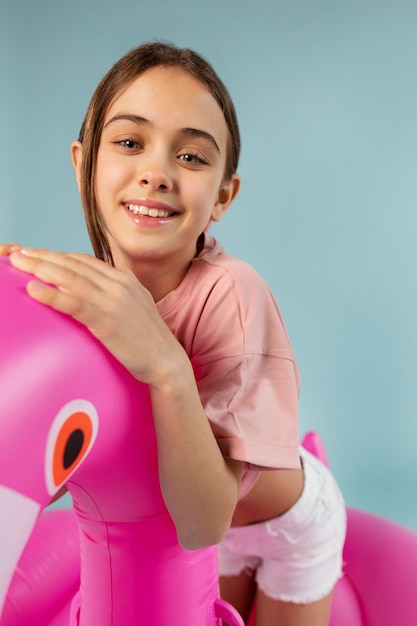 Girl sitting on inflatable flamingo medium shot