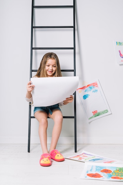 Girl sitting on ladder with drawings 