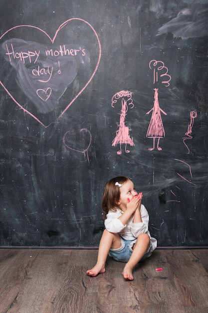 Girl sitting near Happy Mothers Day inscription