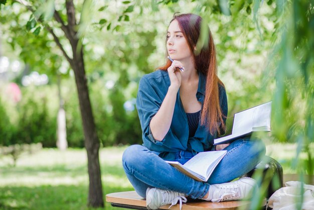 遠くを勉強している公園に座っている女の子