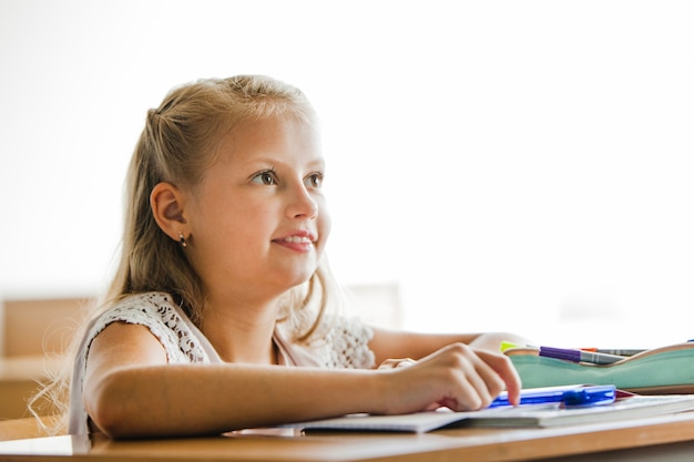 Foto gratuita ragazza seduta alla scrivania scuola sorridente