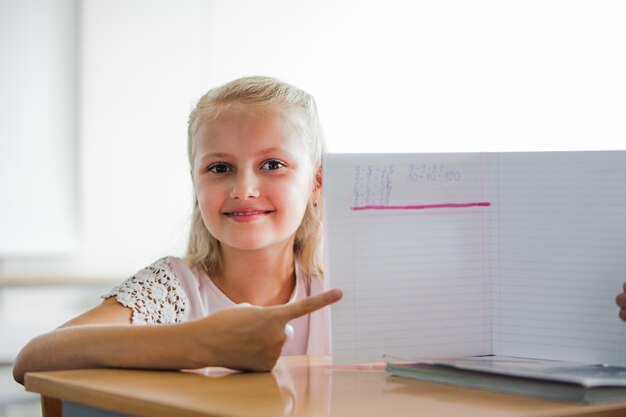 Девочка сидит за школьным столом с ноутбуком