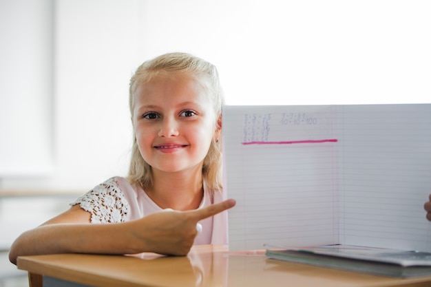 Girl sitting at school table with notebook