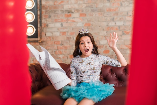 Girl sitting on sofa holding scripts rehearsing