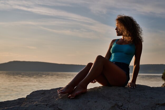 Girl sitting on stones and admiring landscape