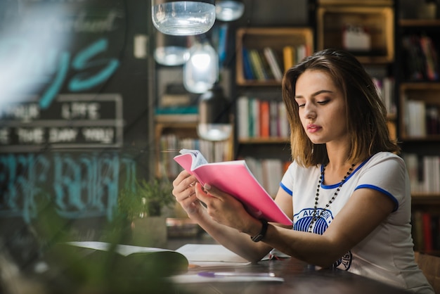 Free photo girl sitting at table holding notebook