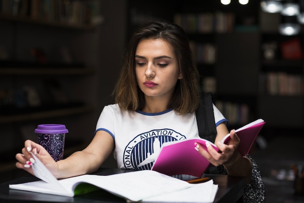 Free photo girl sitting at table reading flipping page