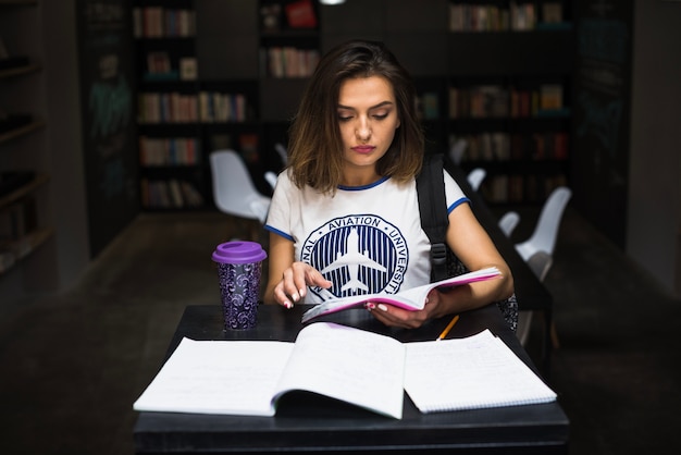 Girl sitting at table reading holding notebook