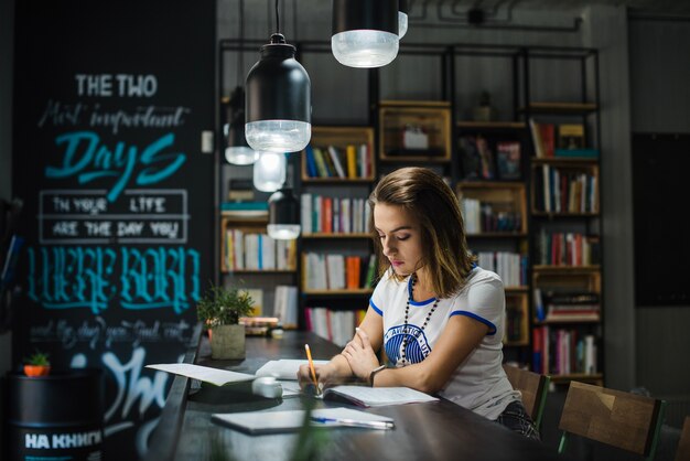 Girl sitting at table with notebooks writing