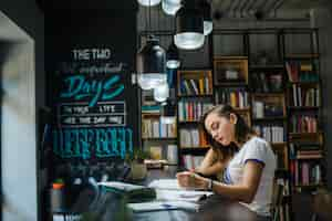 Free photo girl sitting at table with notebooks writing