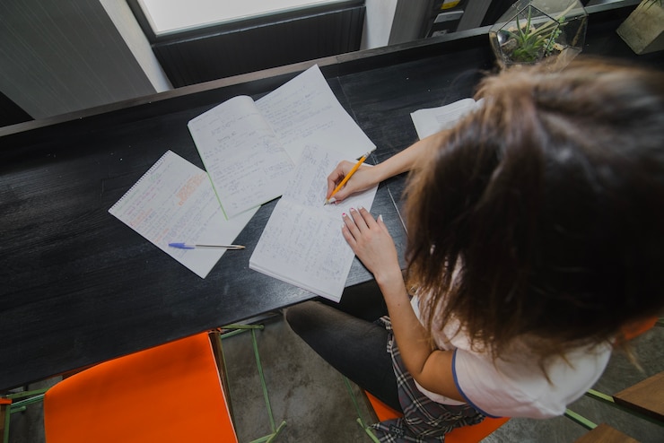 Free Photo girl sitting at table writing