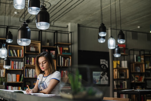 Foto gratuita ragazza seduta a scrittura tavola