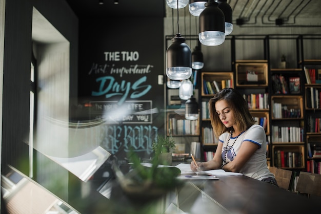 Foto gratuita ragazza seduta a scrittura tavola