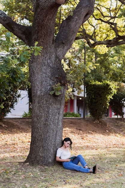 Ragazza che si siede sotto un albero