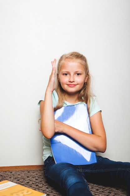 Free photo girl sitting with notebook holding hand up