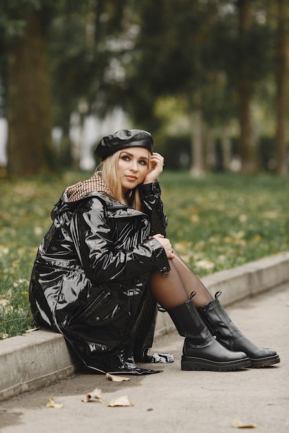 Free photo girl sitting. woman in a black coat. blonde with a black cap.