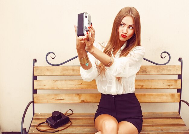 Girl sitting on a wooden bench taking a photo