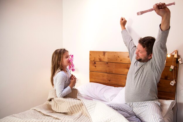 Girl smelling a flower while her father raises her arms