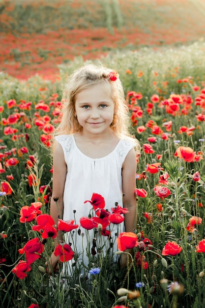 A girl smiles among poppy flowers
