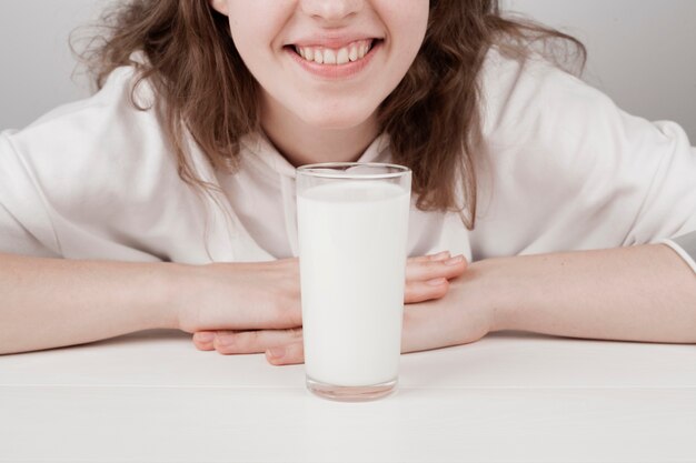Девушка улыбается рядом со стаканом молока