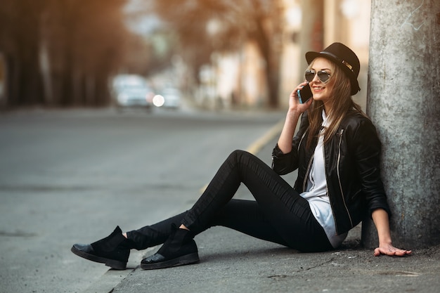 Foto gratuita ragazza che sorride mentre parla sul suo cellulare seduta sul pavimento