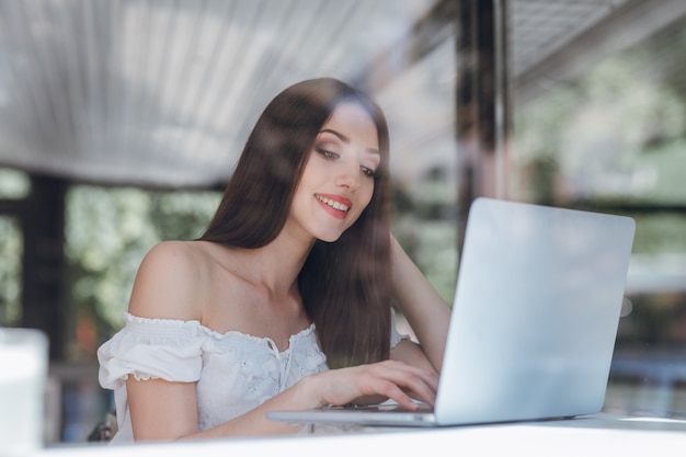 Girl smiling with red painted lips typing on a laptop